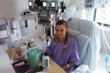 Heart transplant recipient Bec Craven sitting in pyjamas in a hospital ward at Prince Charles Hospital in Brisbane