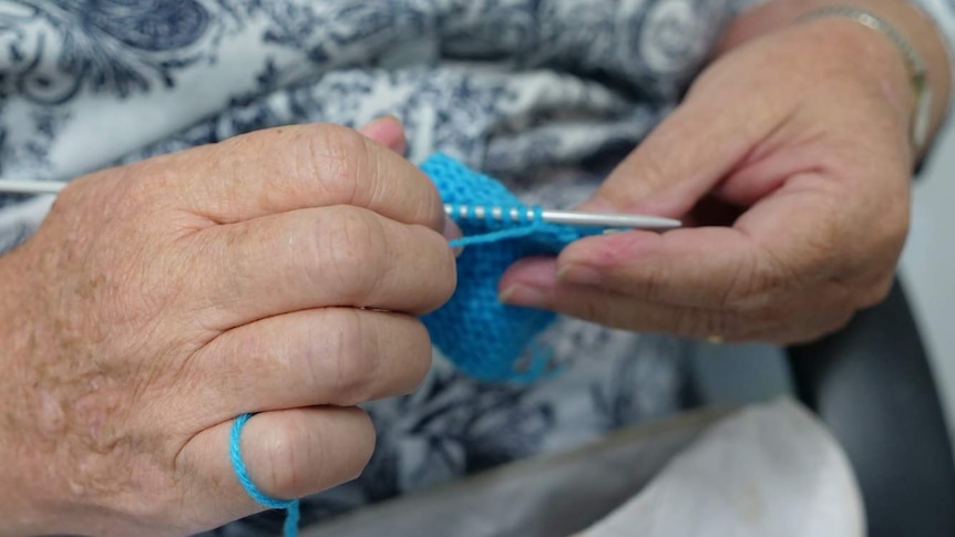 A woman knitting with blue yarn.
