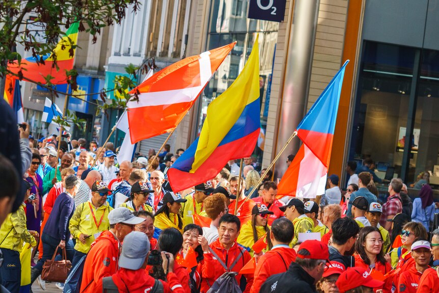 A group of people carrying different country flags march down a street 