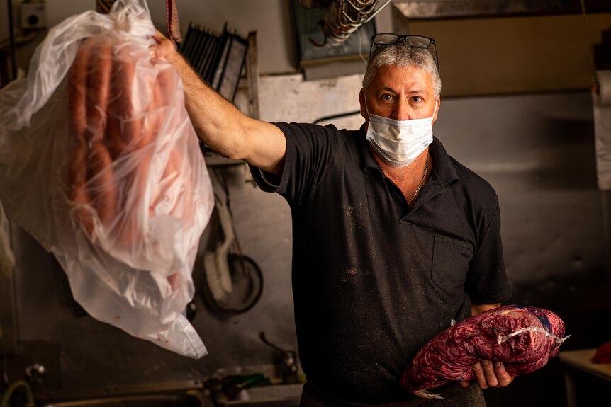 a male butcher holding up sausages