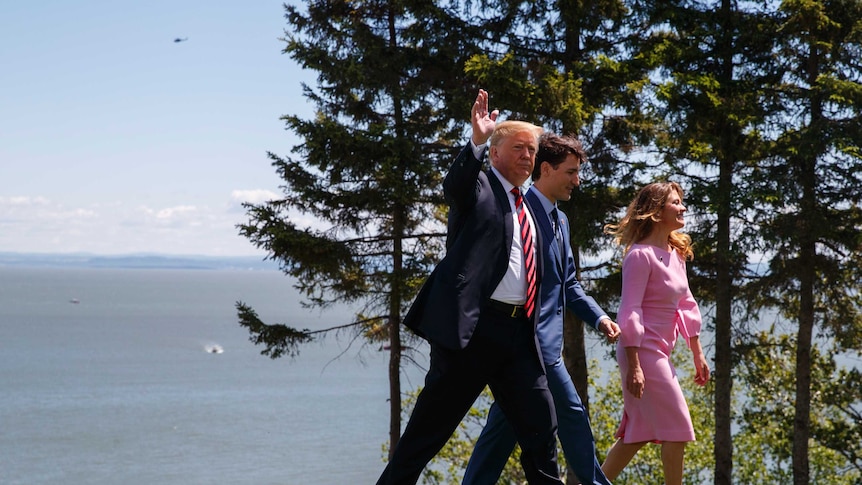 Trump is seen waving as he walks with Justin Trudeau and his wife.