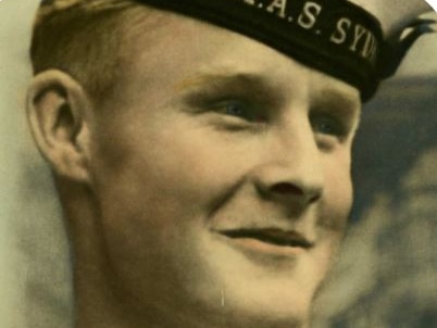 Historical photo of a young man in naval gear, smiling and wearing a hat.