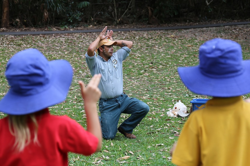 Nigel Stewart mimics a kangaroo as children look on