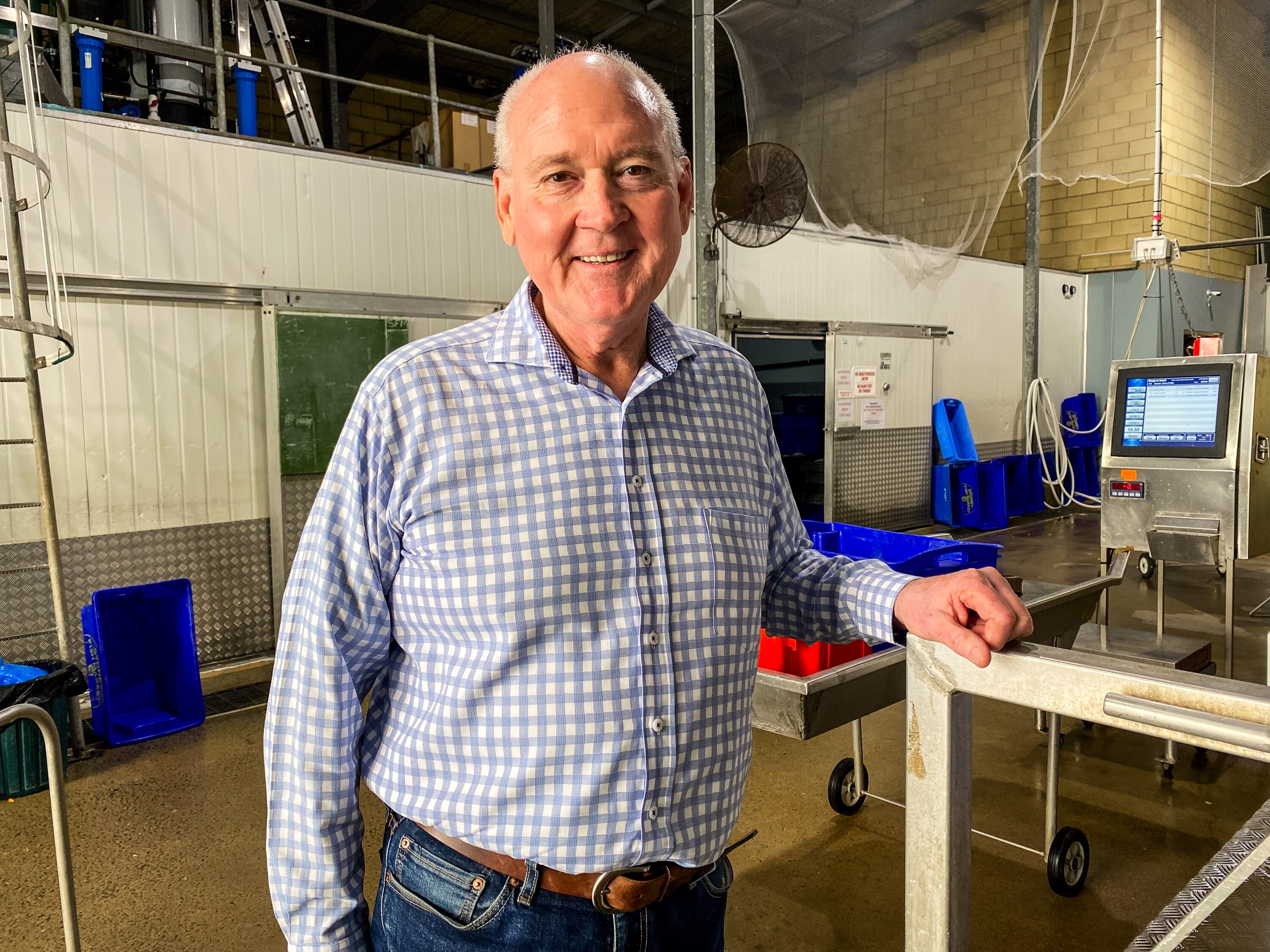 a man standing in a fish processing room smiles at the camera