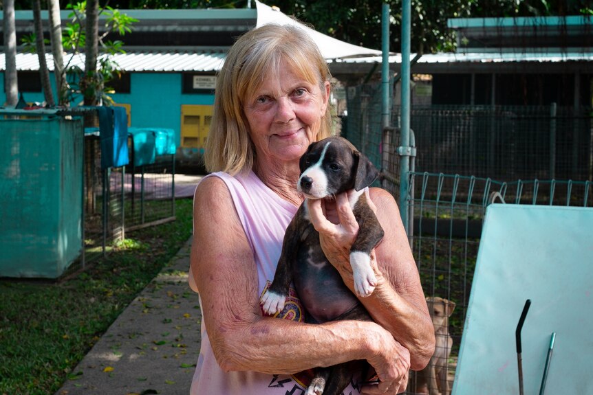 Woman holding puppy in a dog shelter.