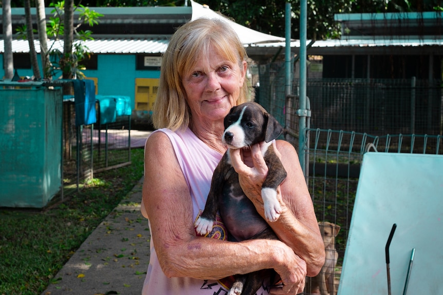 Woman holding puppy in a dog shelter.