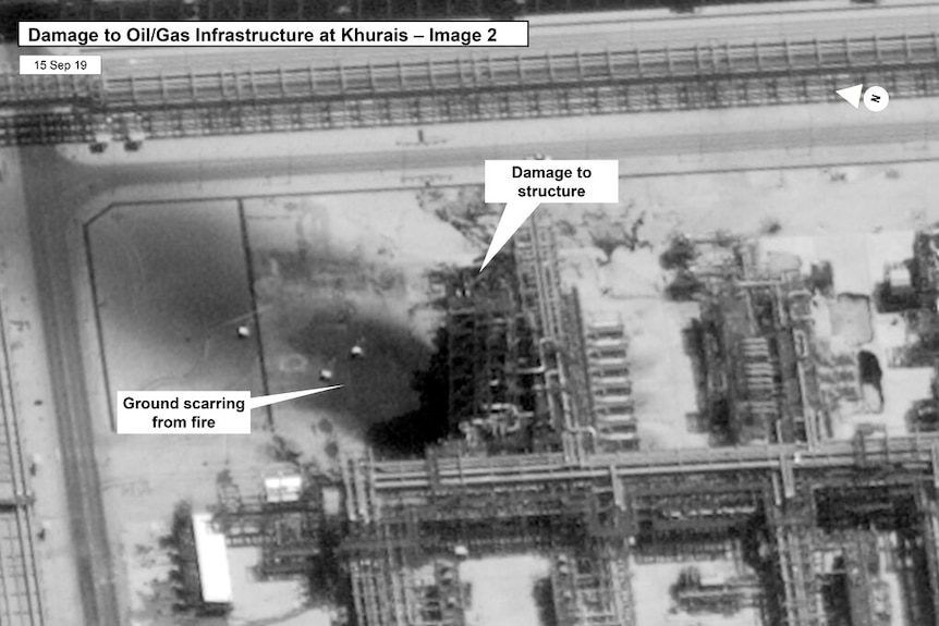A black and white satellite image of a Saudi Arabian oil processing facility, with a charred mark in the centre of the image.