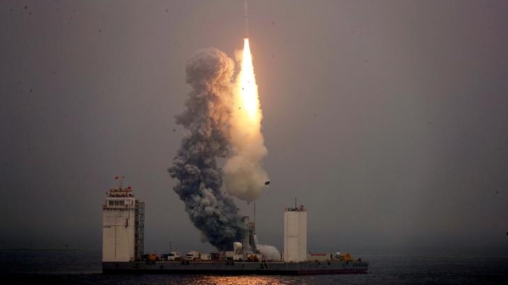 Fire and smoke from rocket takes off from a mobile launch platform on the sea.