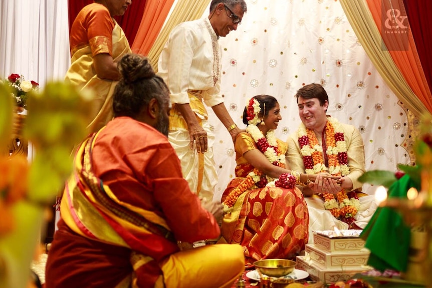 Ahalya Krishinan and Ryan Brown smile at each other during a Hindu wedding.