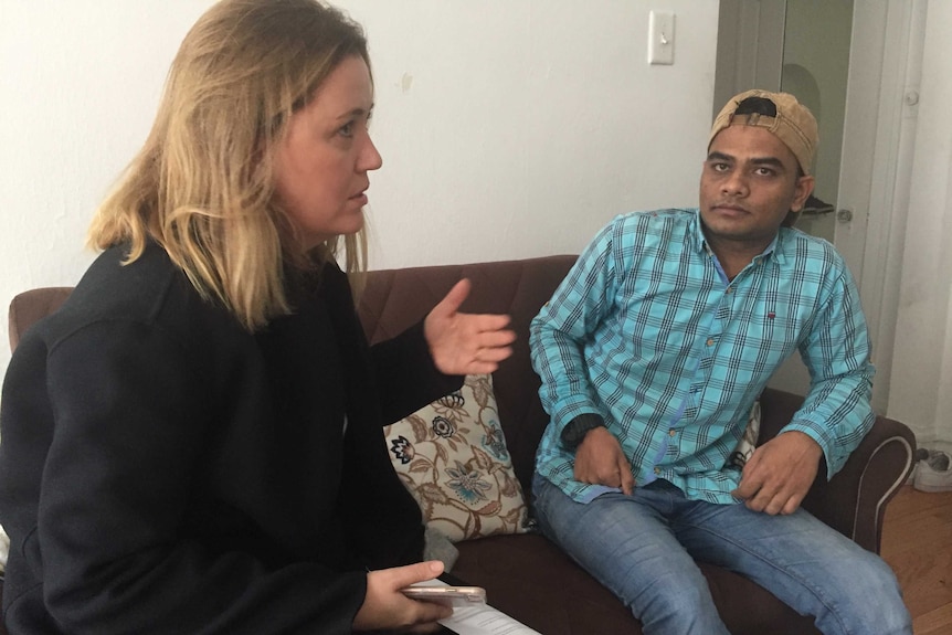 A woman speaks and gestures while sitting next to a man on a couch.