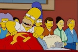 A screengrab from the Simsons with Homer leaning over the body of Chairman Mao. 