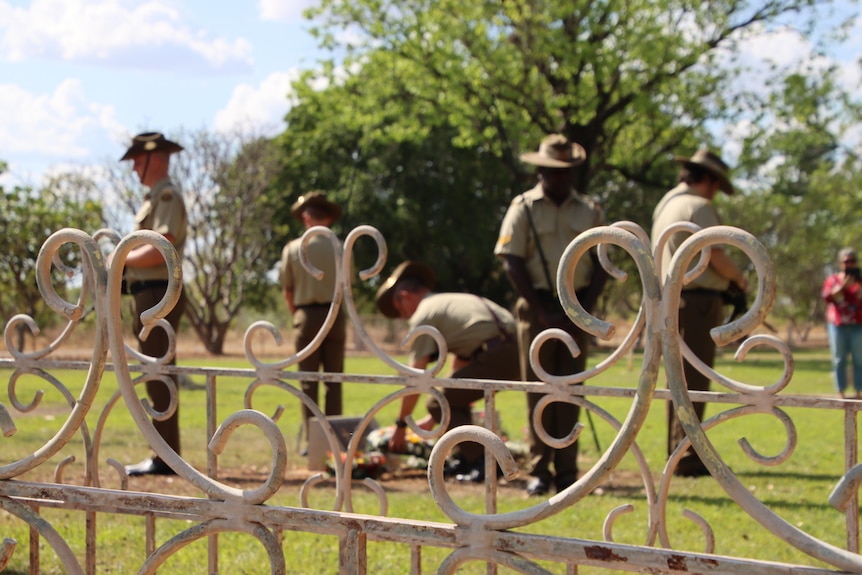 A group of serviceman stand around the grave of World War One war veteran in Katherine.