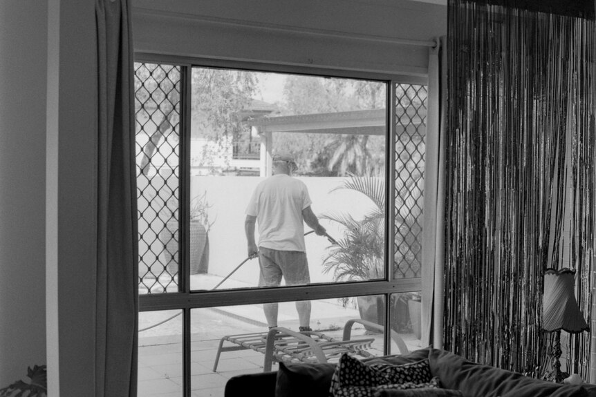 A man holding a hose outside a window