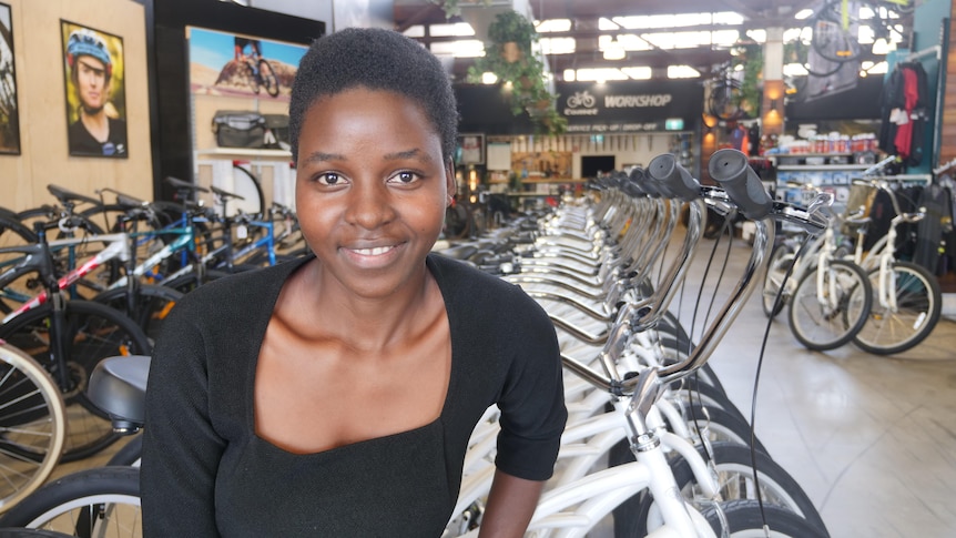 A woman stands in front of a row of bikes in a store