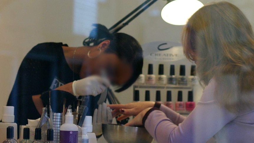 An unidentifiable woman works on another woman's nails at a generic nail salon