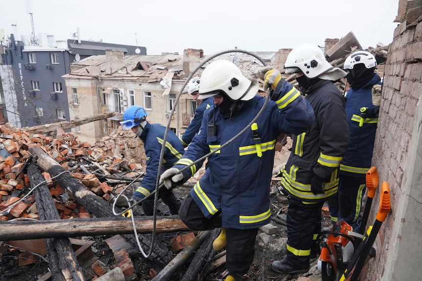 Emergency workers clear rubble off the roof of a residential building.