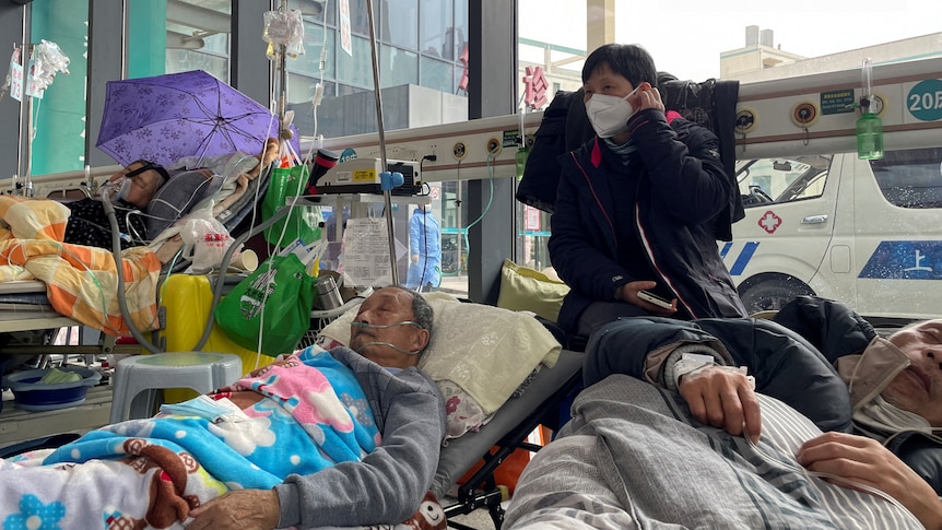 Patients lie on beds in the emergency department of a hospital.