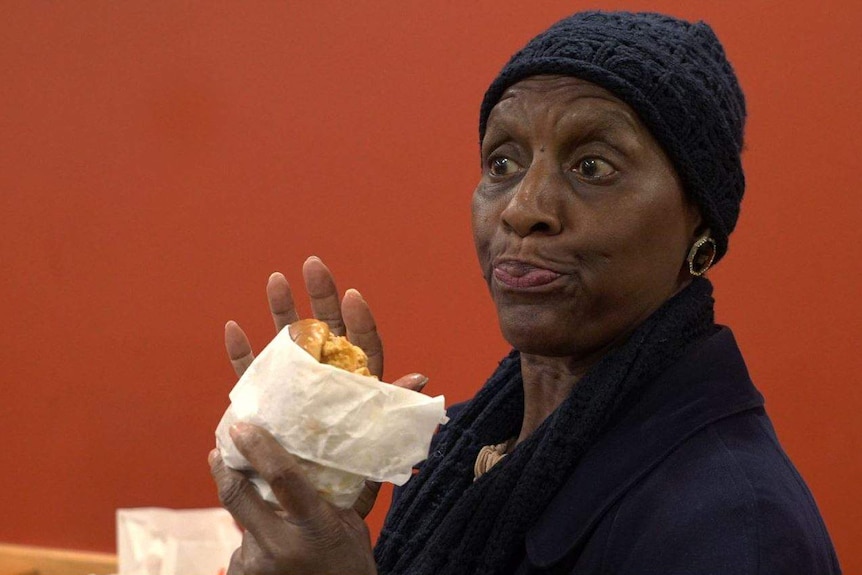 A woman is holding a Popeyes chicken sandwich