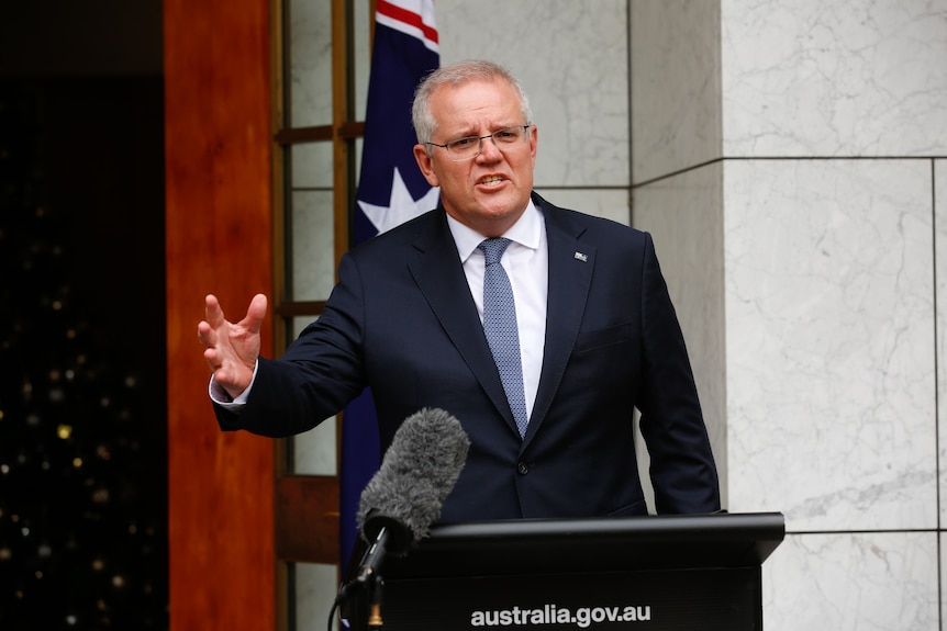 Scott Morrison has his arm outreached while speaking at a lecturn