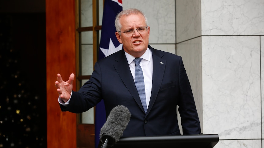 Scott Morrison has his arm outreached while speaking at a lecturn