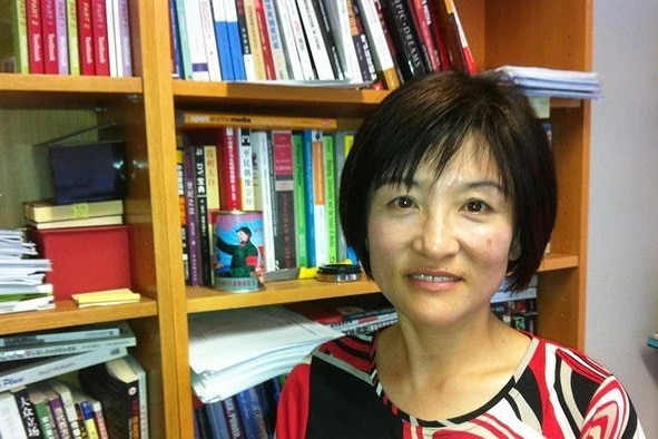 RMIT University professor Haiqing Yu with short hair standing in front of bookshelves