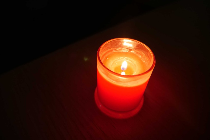 A red candle in a dark room.