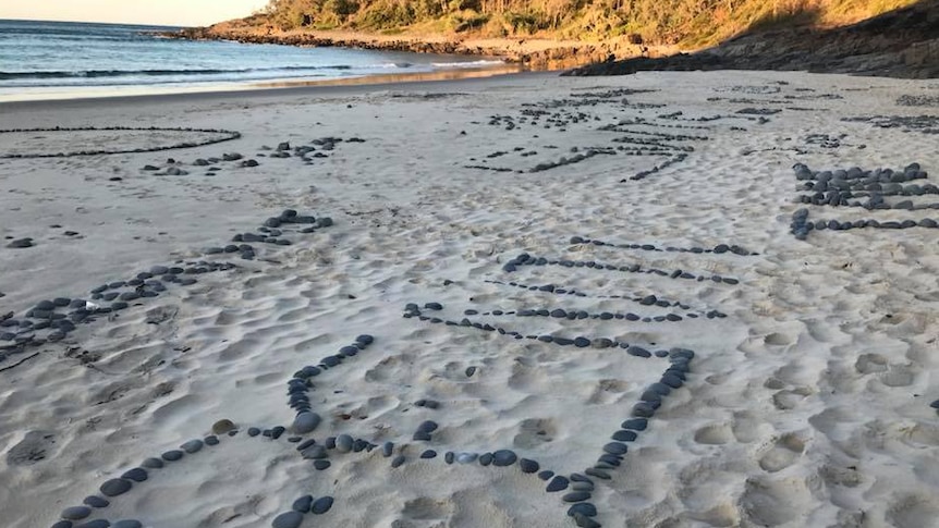 words made up of small rocks on a beach