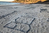 words made up of small rocks on a beach