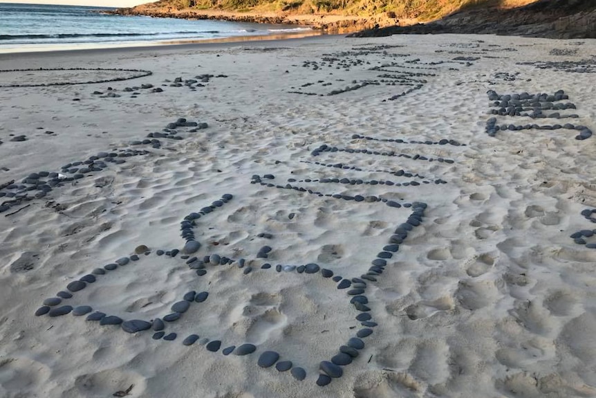 words made up of small rocks on a beach