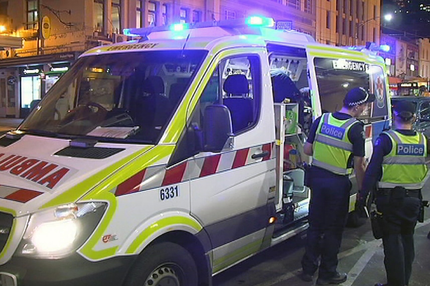Police stand next to an ambulance at Flinders Street Station.
