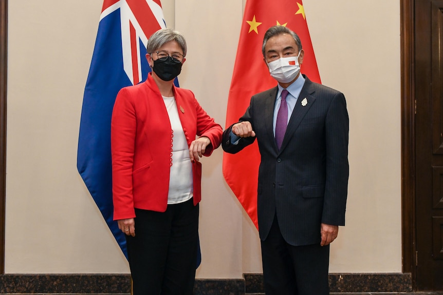 一男一女用手肘冲向镜头，身后挂着澳大利亚和中国国旗。