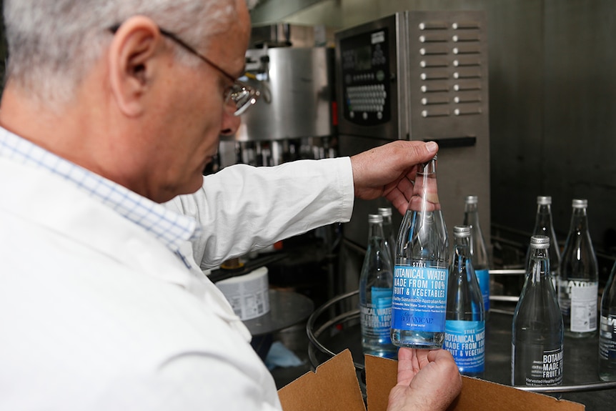 Dr Bruce Kambouris holding and looking at a bottle of water.