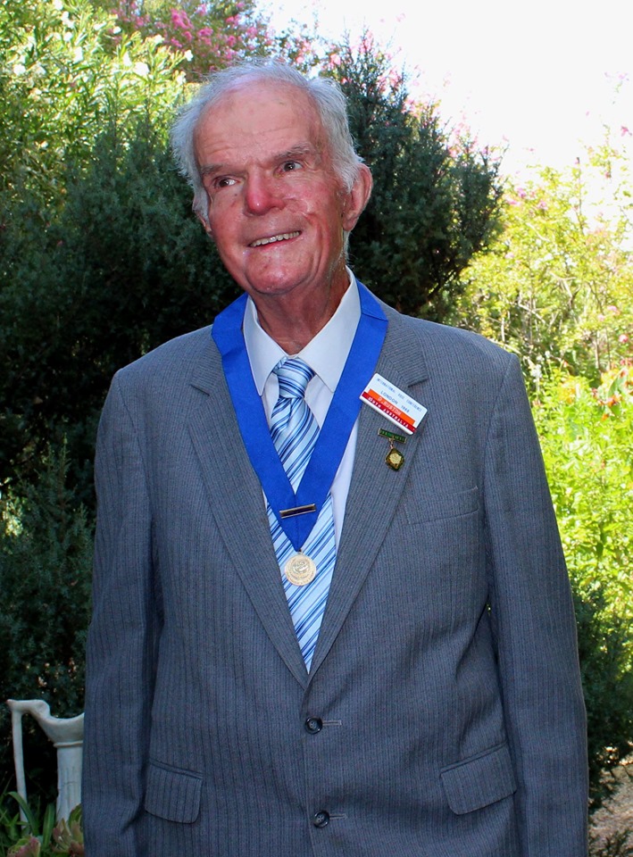 David Ruston standing in a garden with the Dean Hole medal around his neck.