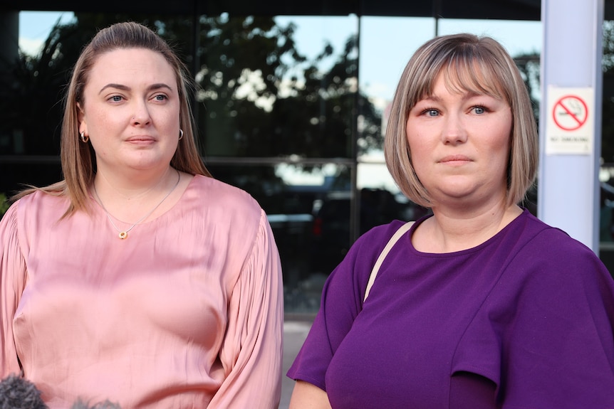 Two women looking sad outside a court house