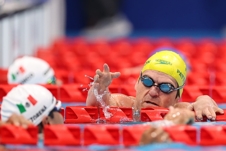 Grant Patterson, in the pool wearing Team Australia swimming cap, puts a hand out to congratulate Arnulfo Castorena