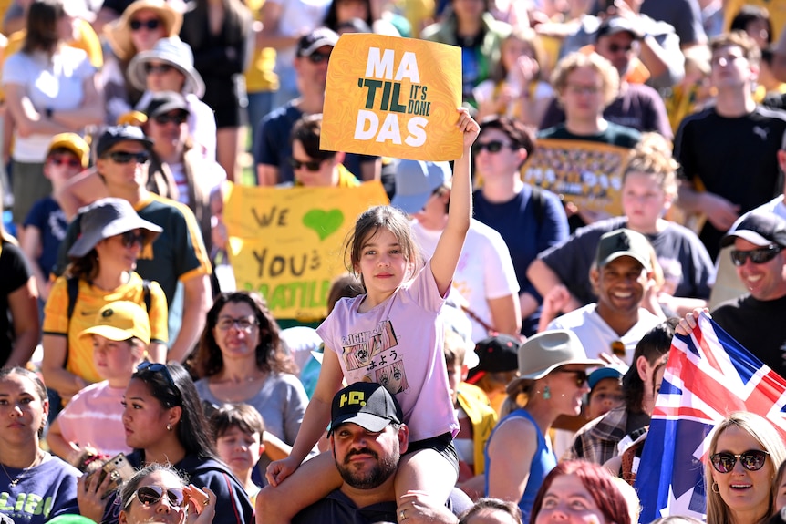A young girl holds up a sign supporting Australia's Matildas at a fan day after the Women's World Cup.