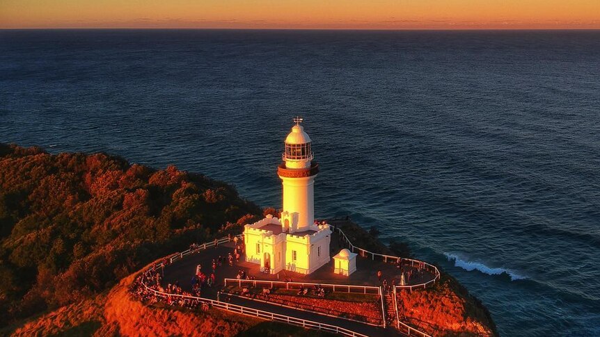 A drone photo of a lighthouse at sunset.