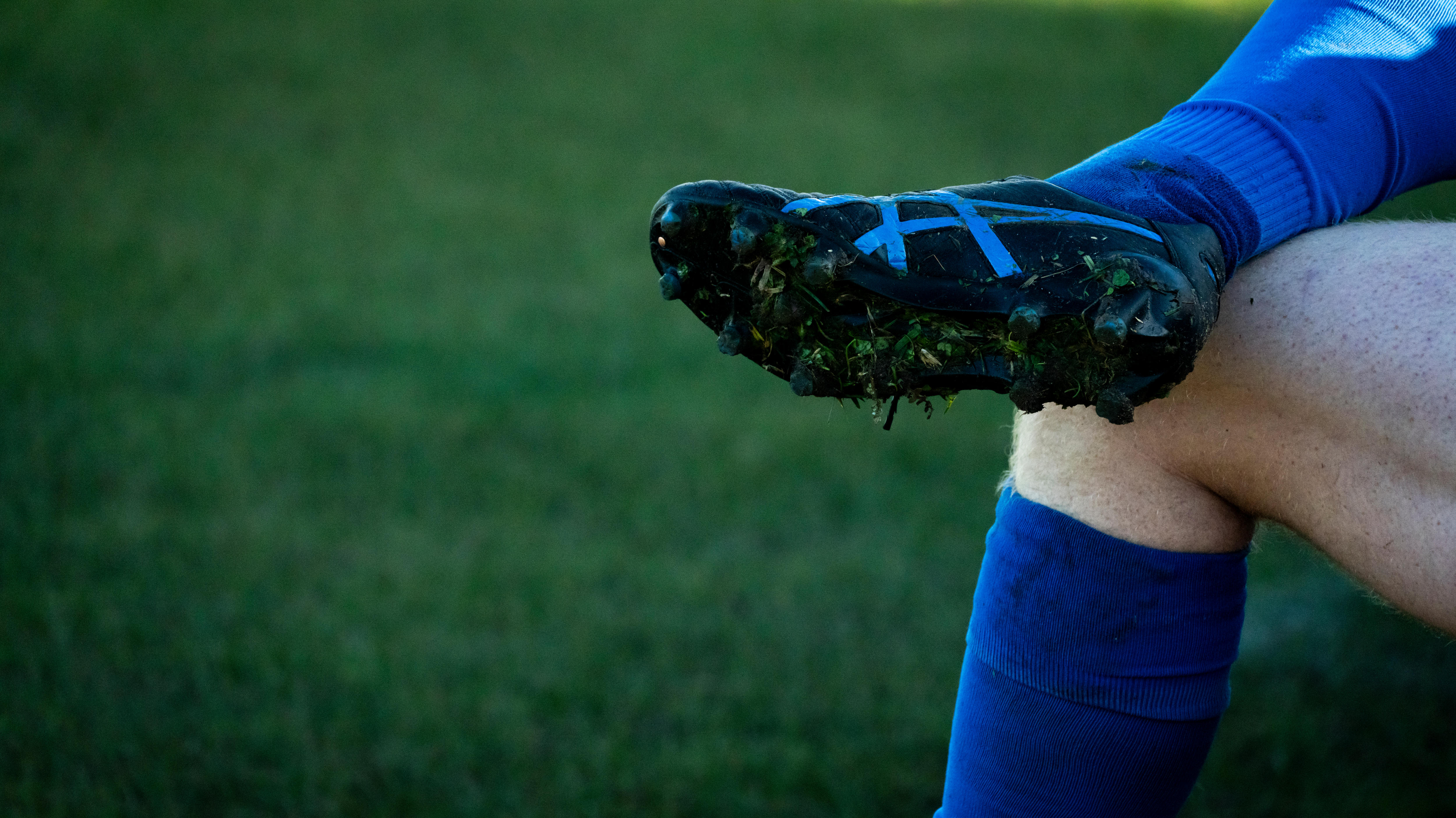 A footballer's leg and boot crossed over his other leg.