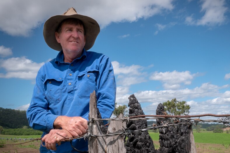 Farmer Tim Doherty standing by a burnt farm post on his property.