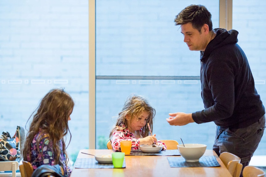 The girls eat breakfast at the table while James watches on.