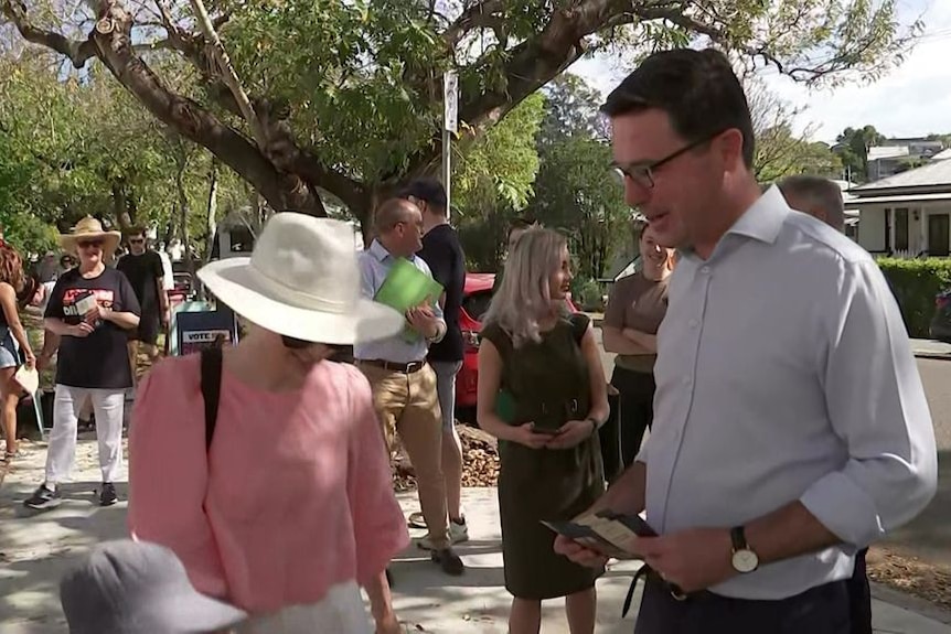 David Littleproud talks to an unidentifiable woman under a tree.