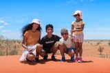 Four children pose for a photo on a red sand dune.