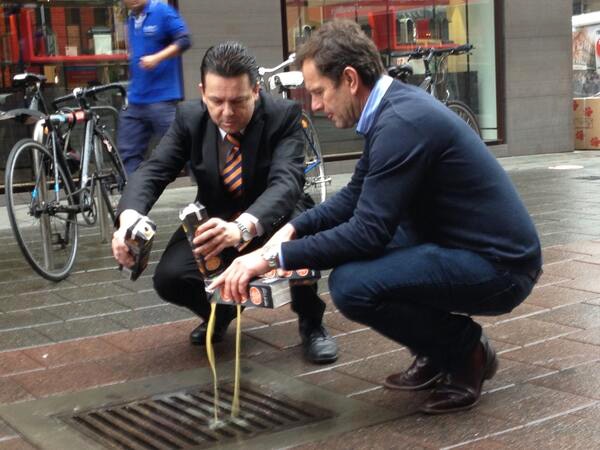 Nick Xenophon and Riverland MP Tim Whetstone pour juice down a drain in a street.