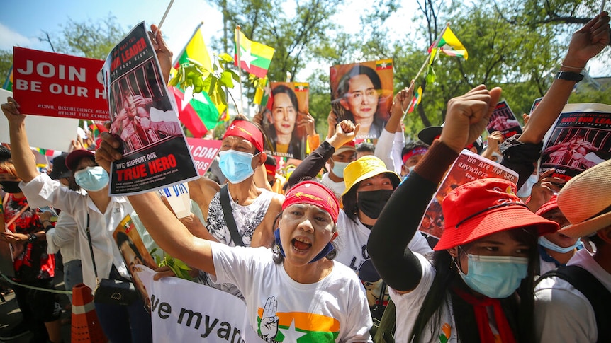 Myanmar nationals living in Thailand hold pictures of deposed Myanmar leader Aung San Suu Kyi.