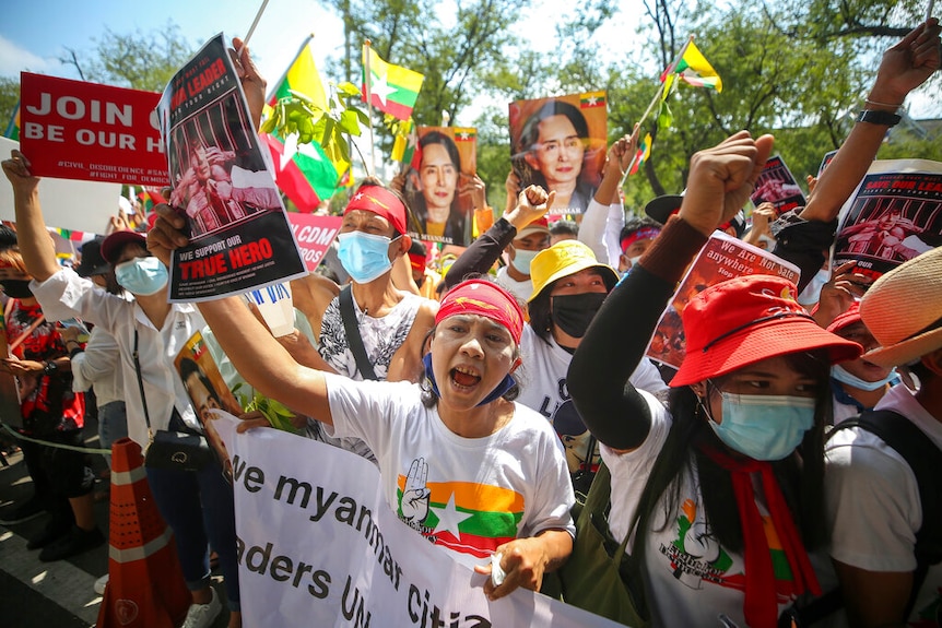 Myanmar nationals living in Thailand hold pictures of deposed Myanmar leader Aung San Suu Kyi.