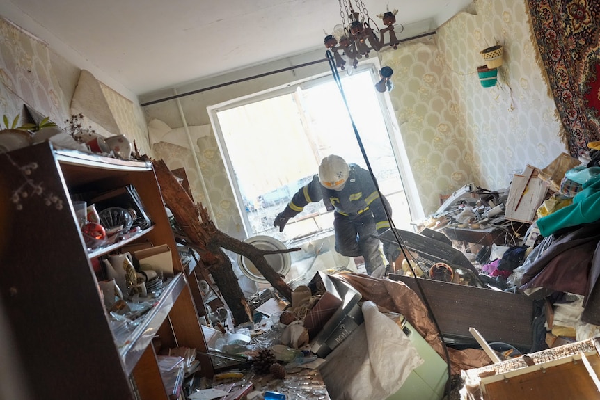 A fire fighter stumbles through wreckage inside an apartment which have been shelled