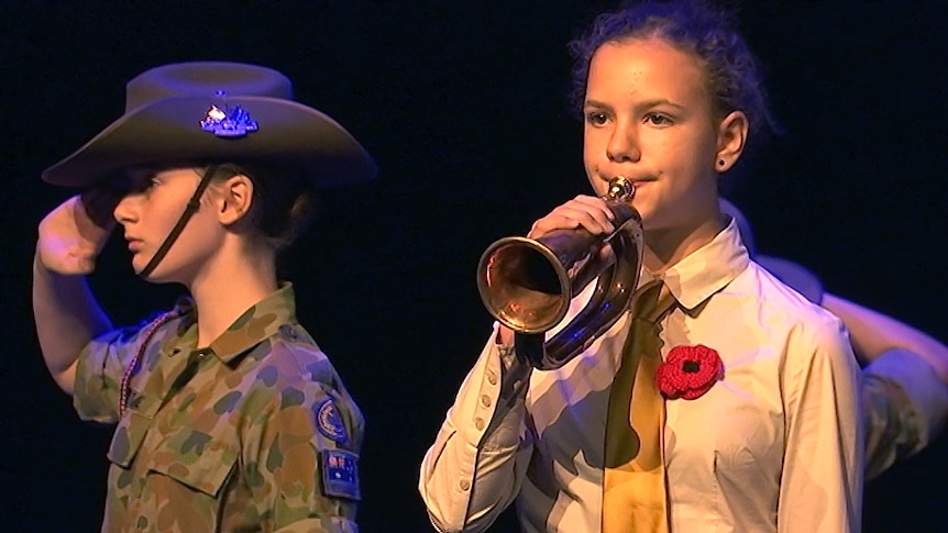 Army cadet salutes while a 12 plays a 100-year-old bugle