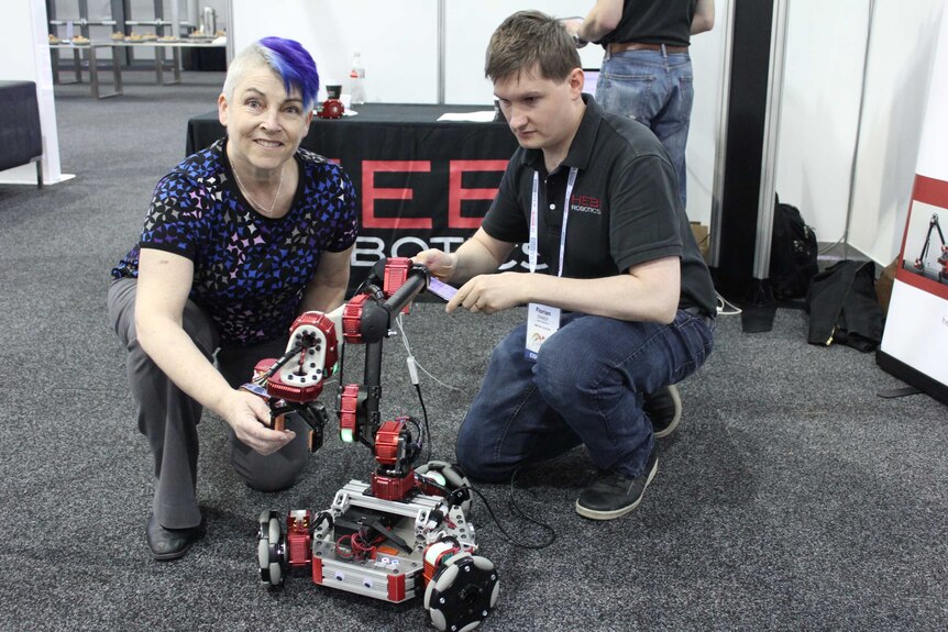 Woman with purple hair uses a robot with a pinching tool.