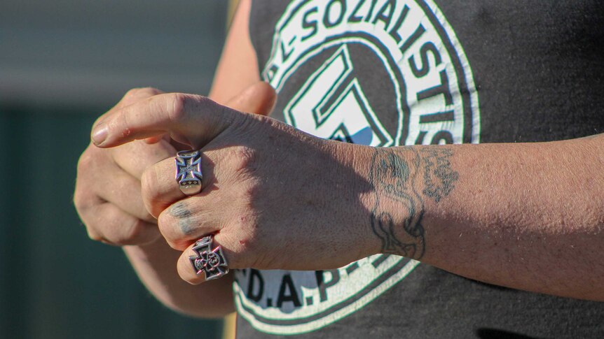 A close up shot of a man's hands with Nazi rings on his fingers
