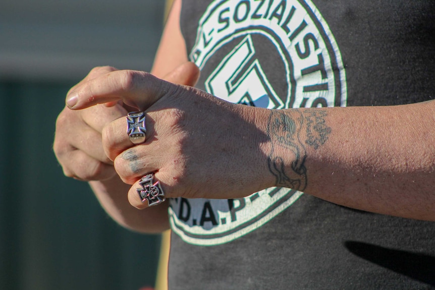 A close up shot of a man's hands with Nazi rings on his fingers